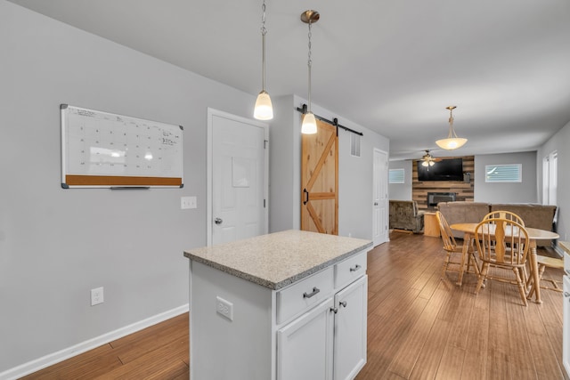 kitchen with white cabinets, decorative light fixtures, a barn door, and ceiling fan