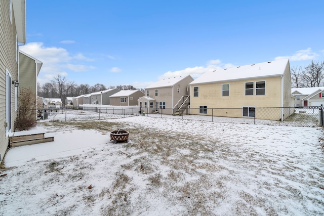 snow covered back of property with an outdoor fire pit