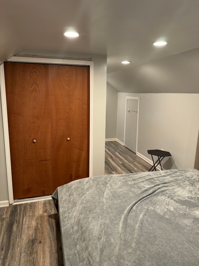 bedroom with dark wood-type flooring and lofted ceiling