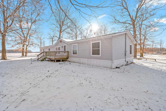 snow covered back of property featuring a deck