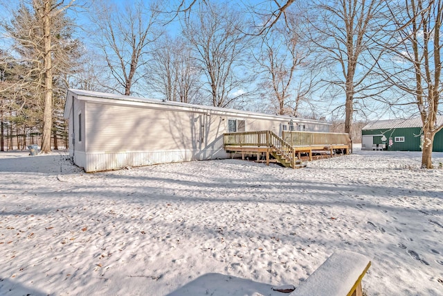 snow covered back of property featuring a wooden deck