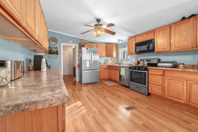 kitchen with appliances with stainless steel finishes, a textured ceiling, vaulted ceiling, crown molding, and light hardwood / wood-style floors