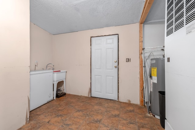 laundry area with electric water heater and a textured ceiling