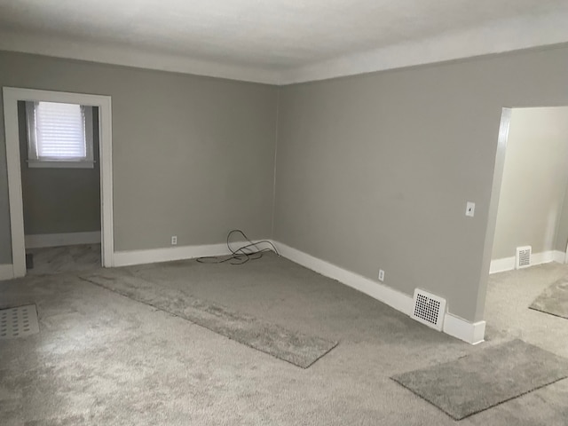 carpeted spare room featuring baseboards and visible vents