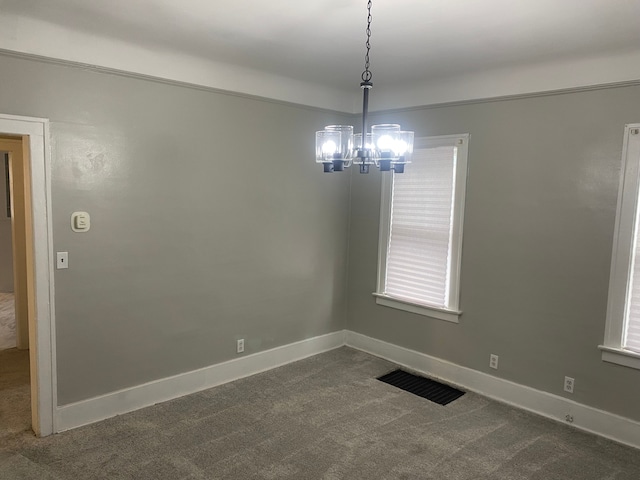 empty room with carpet floors, baseboards, visible vents, and a chandelier