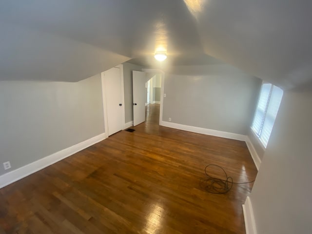 additional living space featuring lofted ceiling and dark wood-type flooring