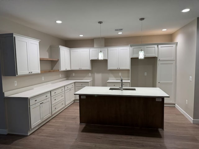 kitchen featuring hanging light fixtures, a center island with sink, dark hardwood / wood-style flooring, white cabinets, and sink