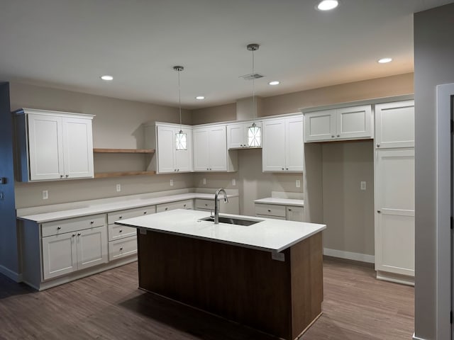 kitchen featuring sink, white cabinetry, hardwood / wood-style floors, hanging light fixtures, and a kitchen island with sink