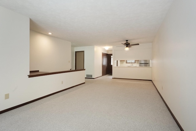 carpeted spare room with ceiling fan, sink, and a textured ceiling