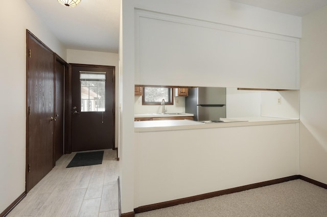 kitchen with stainless steel fridge, dark brown cabinetry, and sink