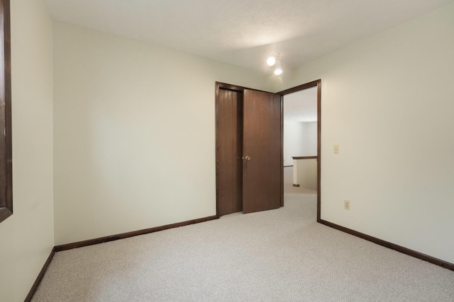 unfurnished bedroom featuring light colored carpet and a closet