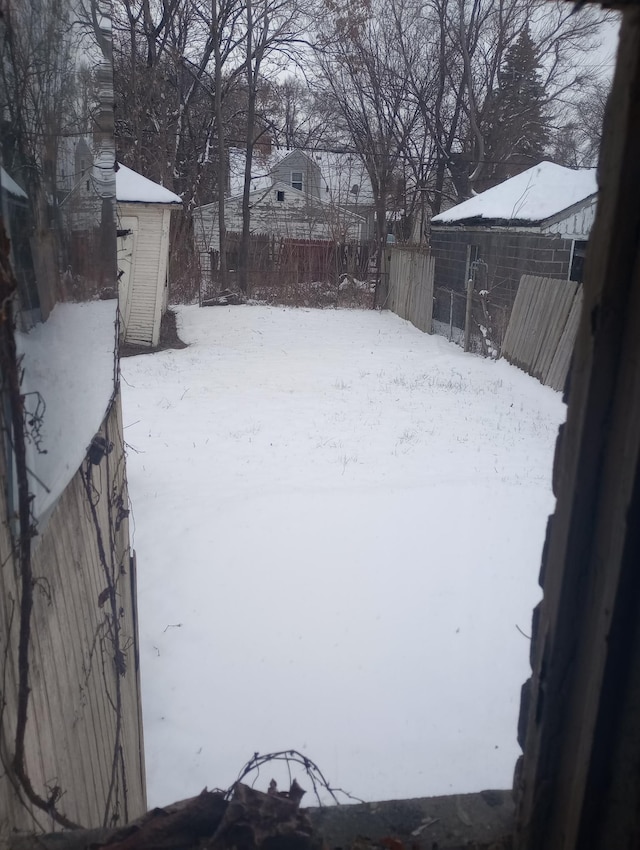 yard layered in snow featuring a storage shed