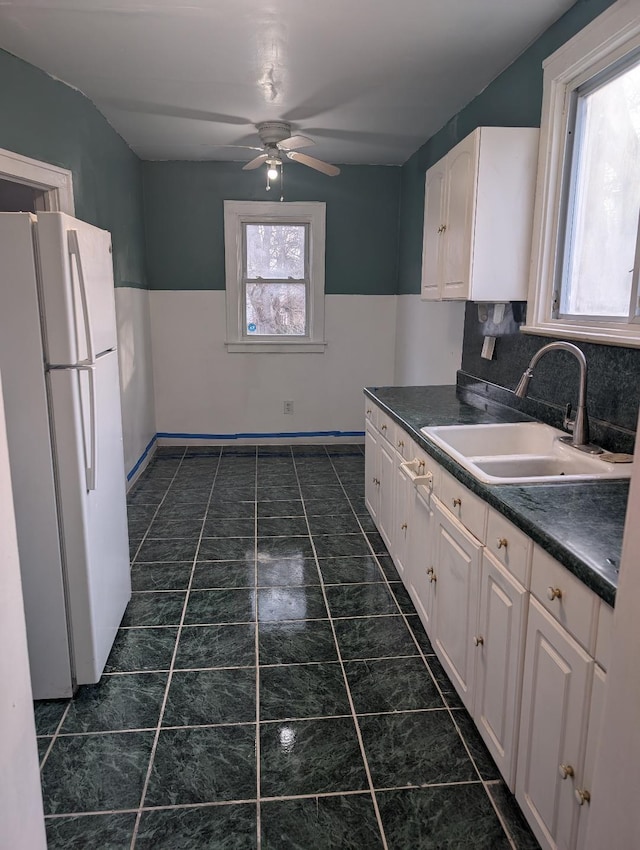 kitchen featuring decorative backsplash, ceiling fan, sink, white refrigerator, and white cabinetry