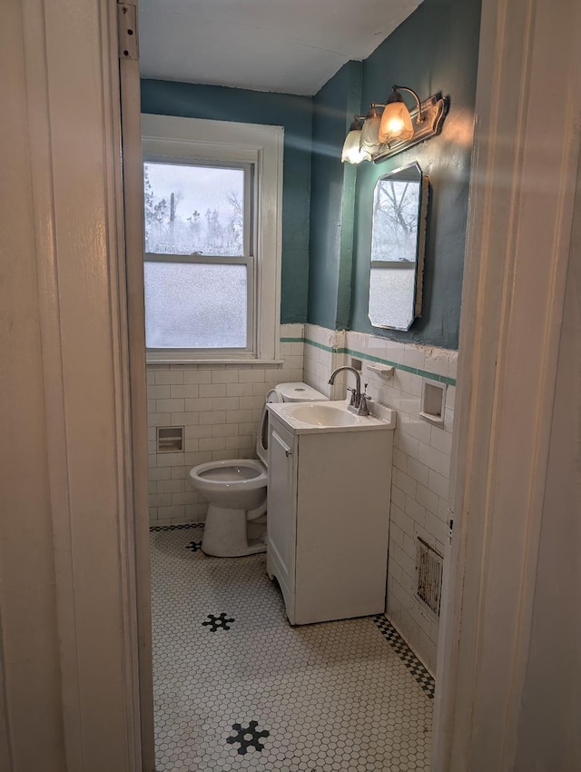 bathroom with tile patterned flooring, vanity, toilet, and tile walls