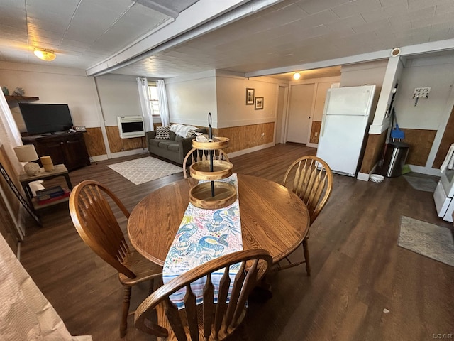 dining area featuring heating unit, dark wood-type flooring, and wood walls