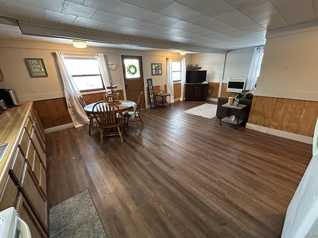 dining space with dark hardwood / wood-style floors, heating unit, and wooden walls