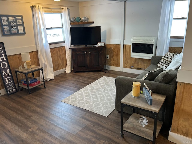 living room with wood walls, dark hardwood / wood-style flooring, and heating unit