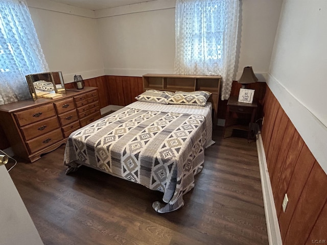 bedroom with wood walls and dark hardwood / wood-style flooring