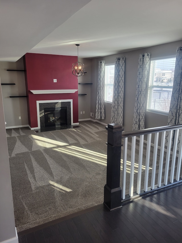 unfurnished living room with a healthy amount of sunlight, dark wood-type flooring, and an inviting chandelier