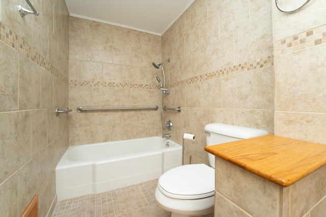 bathroom featuring tiled shower / bath combo, tile patterned floors, toilet, tile walls, and ornamental molding