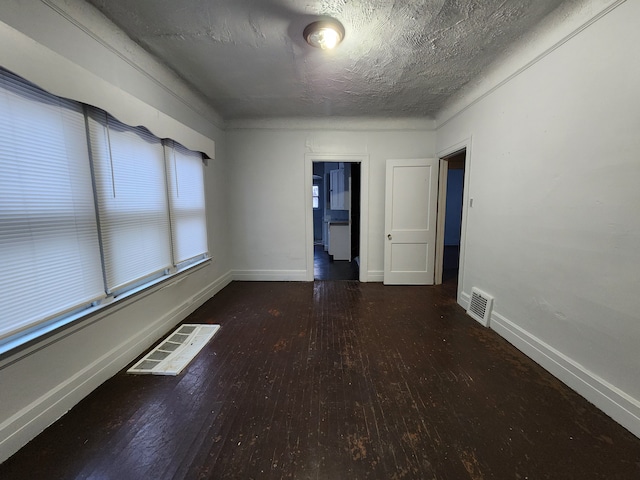 spare room with a textured ceiling and dark hardwood / wood-style flooring