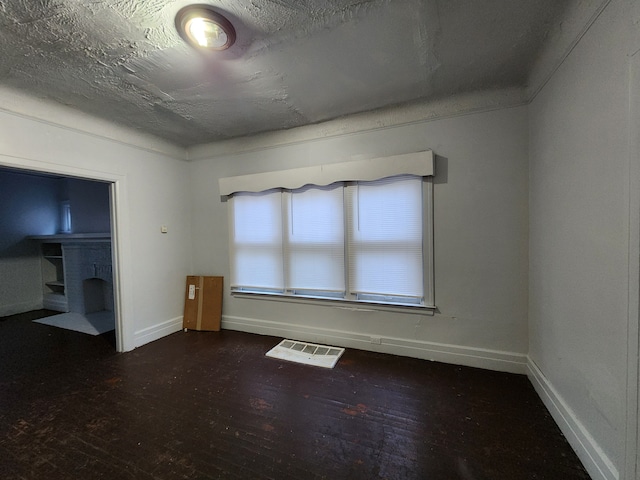 empty room featuring a textured ceiling and dark hardwood / wood-style floors