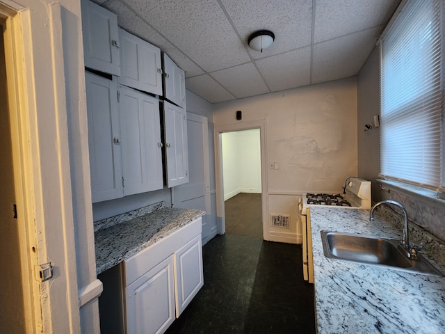 kitchen featuring stainless steel gas stove, white cabinetry, and sink