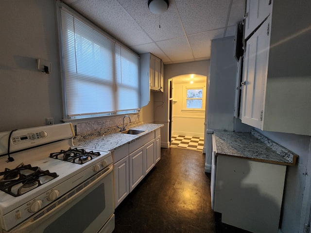 kitchen featuring white cabinetry, sink, light stone counters, and white gas range oven