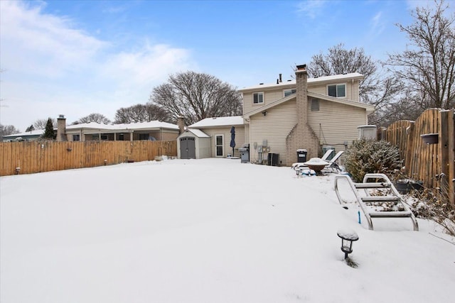 snow covered rear of property with cooling unit and a storage unit