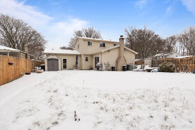 snow covered back of property featuring central AC unit and a shed