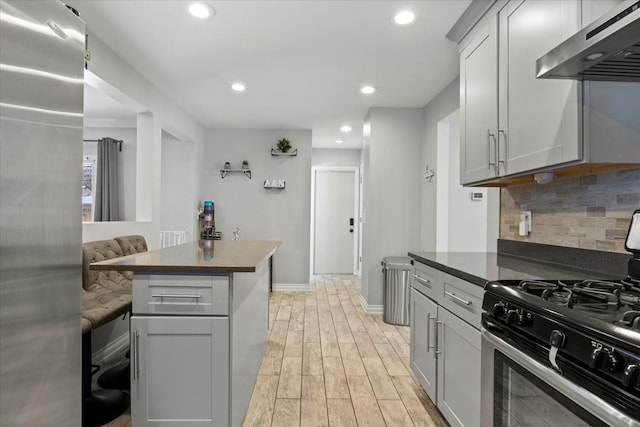 kitchen featuring gray cabinets, a kitchen breakfast bar, ventilation hood, and stainless steel appliances