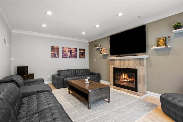 living room featuring light hardwood / wood-style floors, a tile fireplace, and crown molding