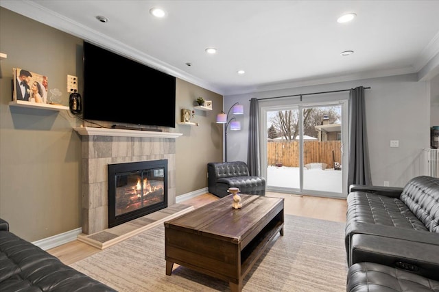 living room featuring light hardwood / wood-style floors, ornamental molding, and a fireplace