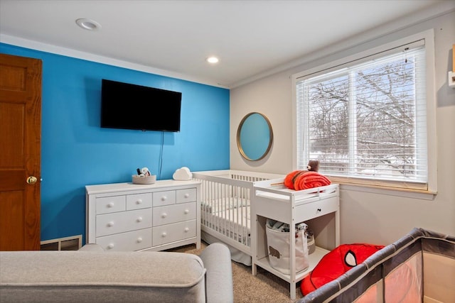 carpeted bedroom with a nursery area and crown molding