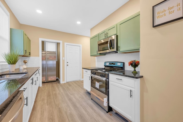 kitchen featuring white cabinetry, appliances with stainless steel finishes, green cabinets, and dark stone counters