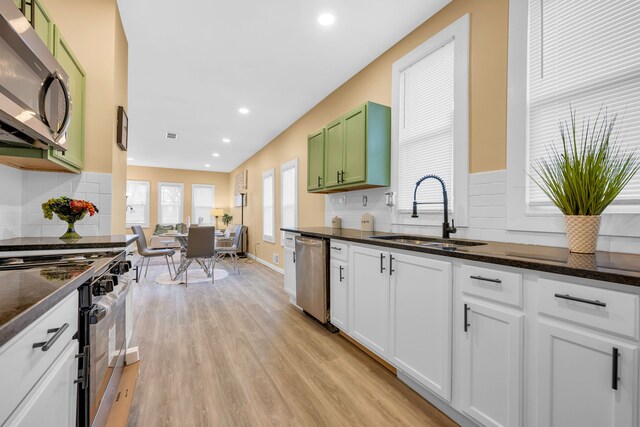 kitchen with green cabinets, appliances with stainless steel finishes, sink, white cabinetry, and light hardwood / wood-style floors