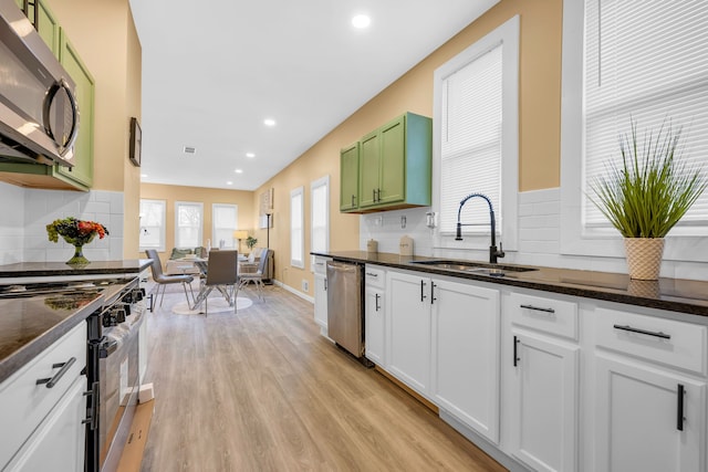 kitchen with sink, white cabinetry, light wood-type flooring, appliances with stainless steel finishes, and green cabinets