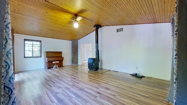 unfurnished living room with lofted ceiling, wood ceiling, light wood-type flooring, and a wood stove