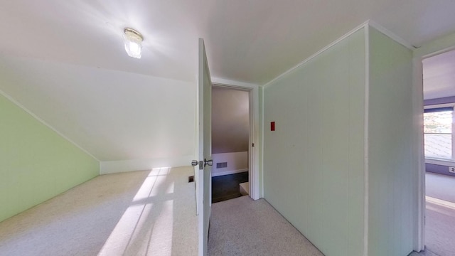 hallway featuring light carpet, vaulted ceiling, and ornamental molding