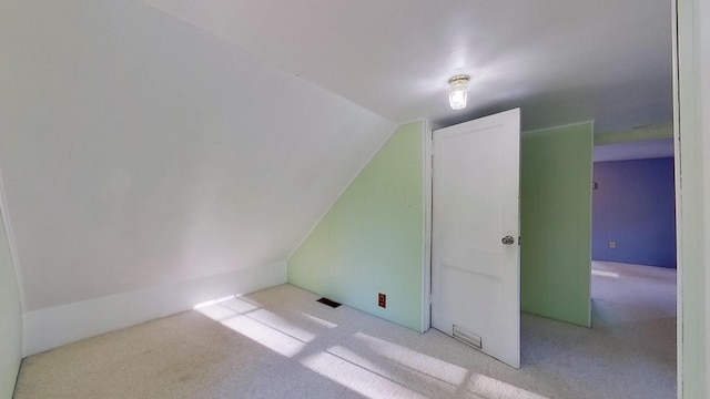 bonus room with vaulted ceiling and light carpet