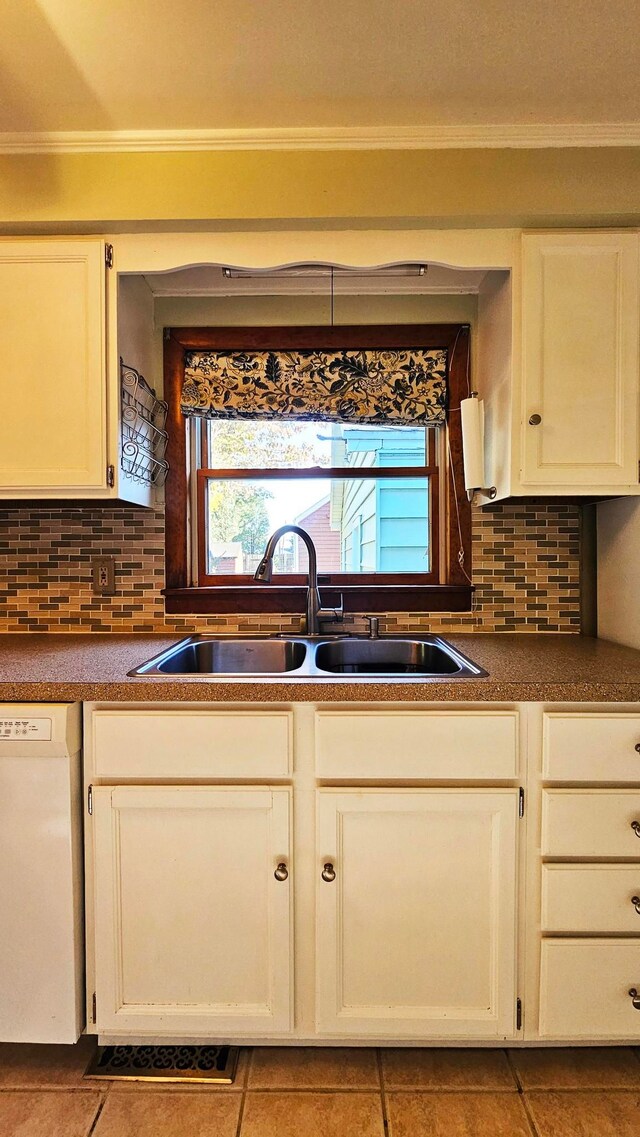 kitchen with sink, tasteful backsplash, ornamental molding, white dishwasher, and white cabinets