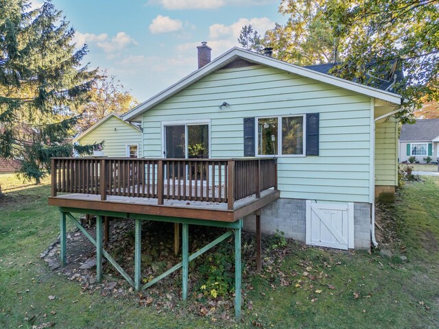 back of property with a wooden deck and a lawn