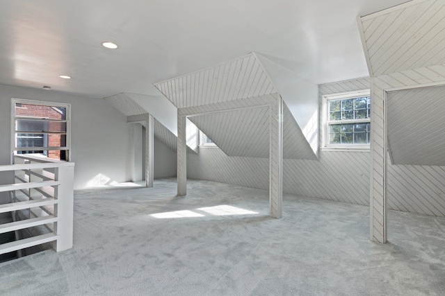 bonus room with wood walls and light colored carpet