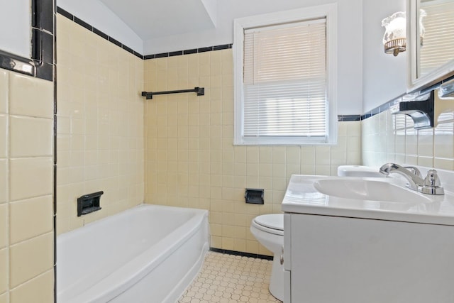 bathroom featuring a tub, vanity, tile walls, and toilet