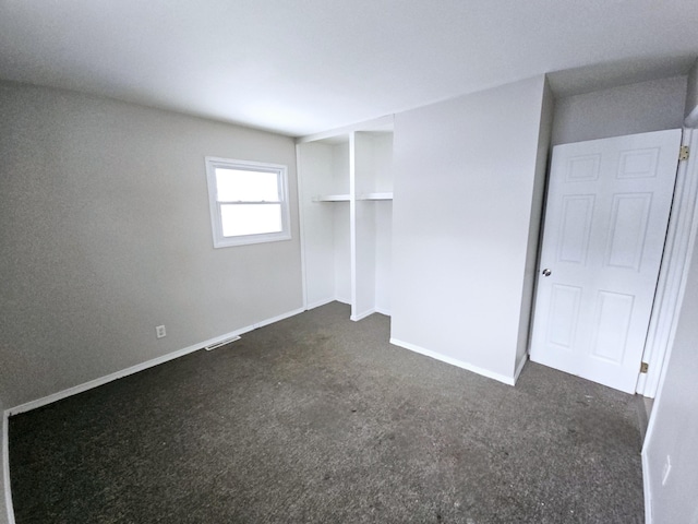 unfurnished bedroom with a closet and dark colored carpet