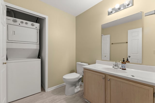 bathroom featuring stacked washer and dryer, vanity, and toilet