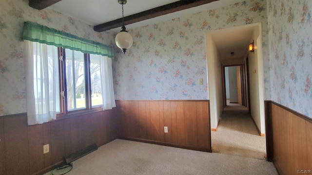 unfurnished room featuring light carpet, wooden walls, and beamed ceiling