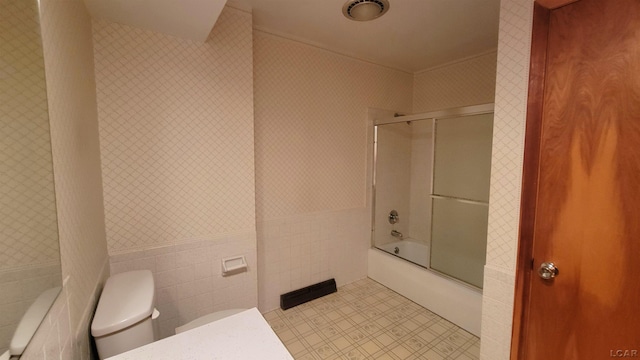 bathroom with enclosed tub / shower combo, tile walls, and toilet