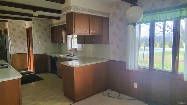 kitchen with white refrigerator, sink, hanging light fixtures, beam ceiling, and kitchen peninsula