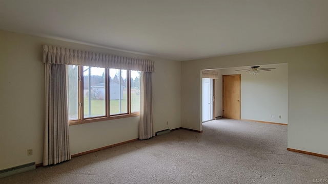 empty room featuring ceiling fan, light colored carpet, and a baseboard heating unit